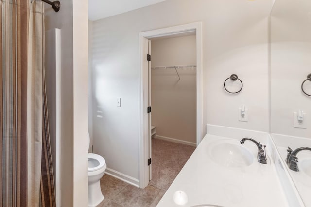 full bathroom featuring double vanity, toilet, tile patterned flooring, a walk in closet, and a sink