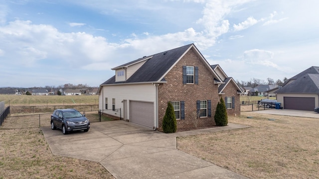 view of side of home with concrete driveway, an attached garage, fence, a yard, and brick siding