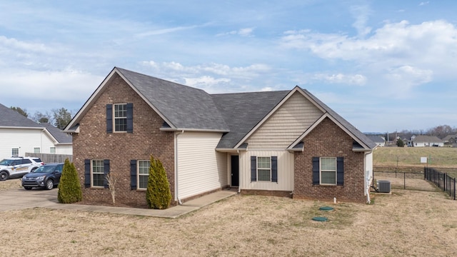 traditional-style home with brick siding, fence, central AC, and a front yard