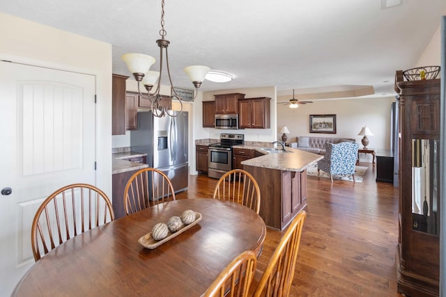 dining area with dark wood-style floors and ceiling fan with notable chandelier