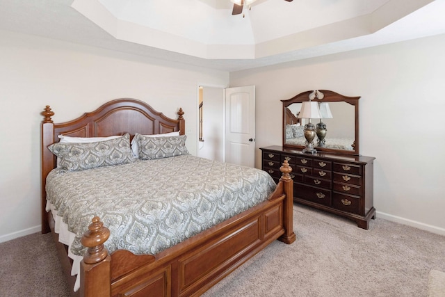 bedroom with baseboards, a raised ceiling, and light colored carpet