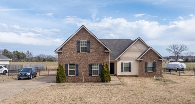 view of front of home with a front yard, fence, and brick siding