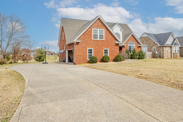 traditional-style house with brick siding, a shingled roof, an attached garage, a front yard, and driveway