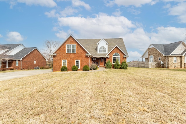 traditional-style house with a front yard, fence, and brick siding