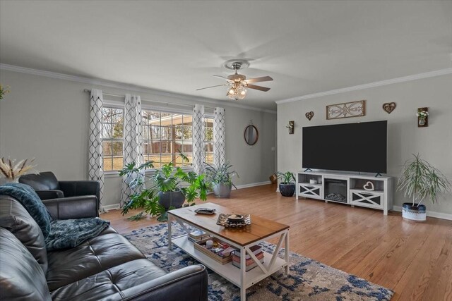 living area with baseboards, wood finished floors, and crown molding