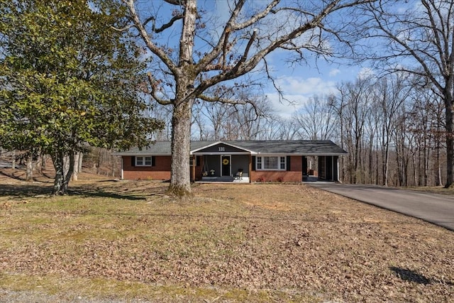 single story home featuring aphalt driveway, a front yard, brick siding, and a carport