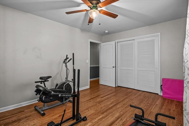 exercise area featuring a ceiling fan, baseboards, and wood finished floors