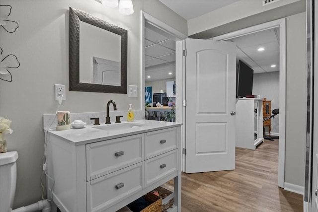 bathroom with toilet, wood finished floors, and vanity