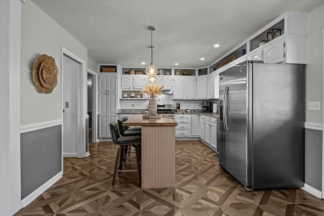 kitchen with white cabinets, tasteful backsplash, stainless steel appliances, and a center island