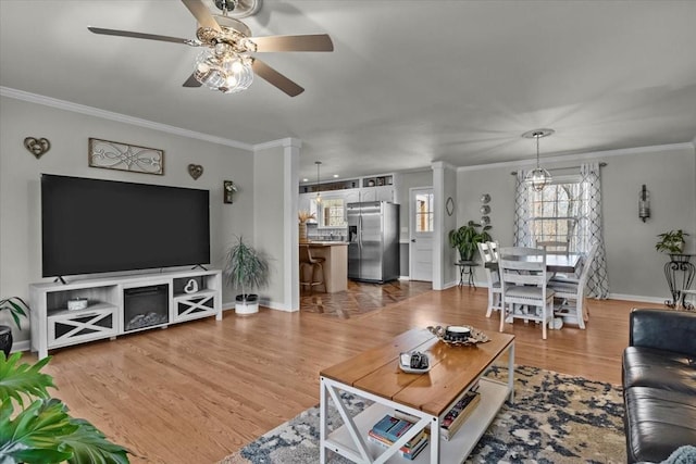 living area featuring ceiling fan, ornamental molding, wood finished floors, and ornate columns