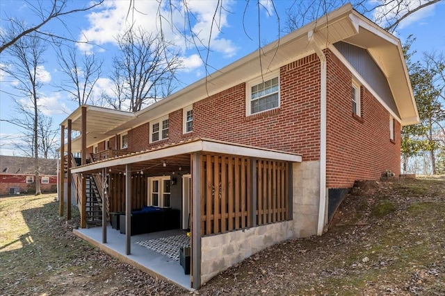 back of property featuring a patio area, brick siding, and stairway