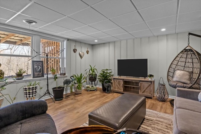 living area with visible vents, a drop ceiling, and wood finished floors