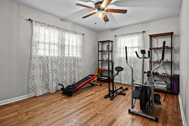 exercise room featuring baseboards, a ceiling fan, and wood finished floors