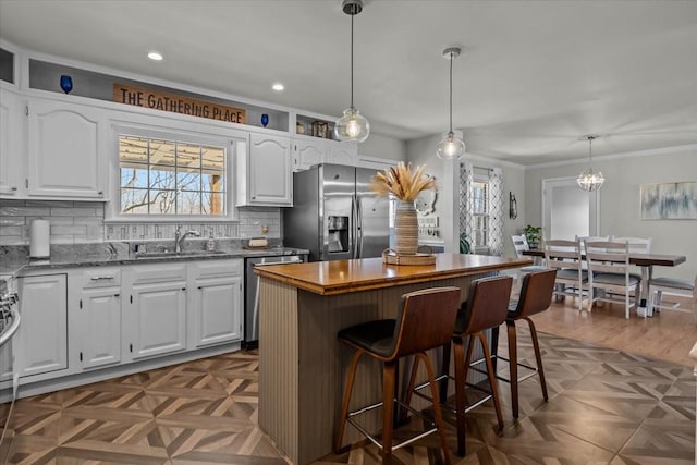 kitchen featuring stainless steel appliances, white cabinets, a healthy amount of sunlight, and a sink