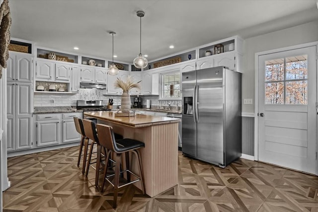 kitchen featuring under cabinet range hood, white cabinetry, appliances with stainless steel finishes, a center island, and open shelves