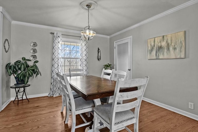 dining area featuring a notable chandelier, baseboards, wood finished floors, and crown molding