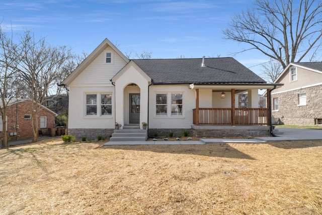 view of front of home featuring a front lawn, covered porch, and a shingled roof