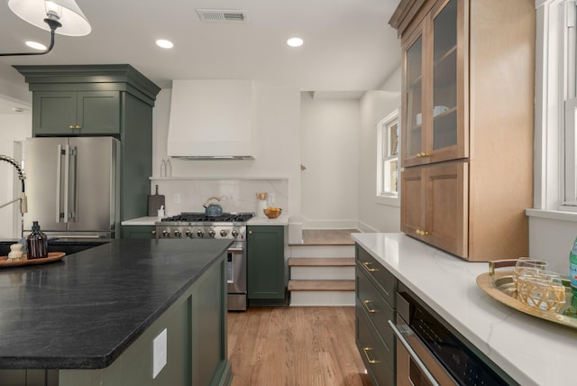kitchen featuring visible vents, premium range hood, light wood-style floors, green cabinets, and high quality appliances