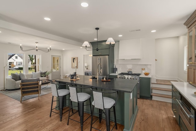 kitchen with a notable chandelier, high end appliances, wood finished floors, and a breakfast bar