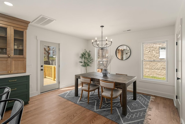 dining area with light wood-style flooring, baseboards, visible vents, and a chandelier
