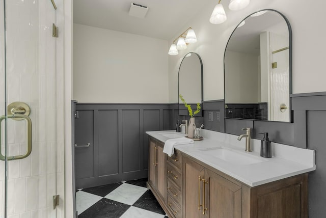 full bath featuring double vanity, a decorative wall, a wainscoted wall, and a sink