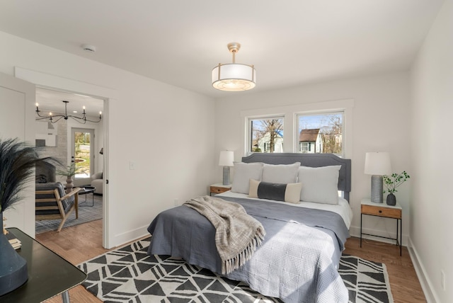 bedroom with baseboards, an inviting chandelier, and wood finished floors