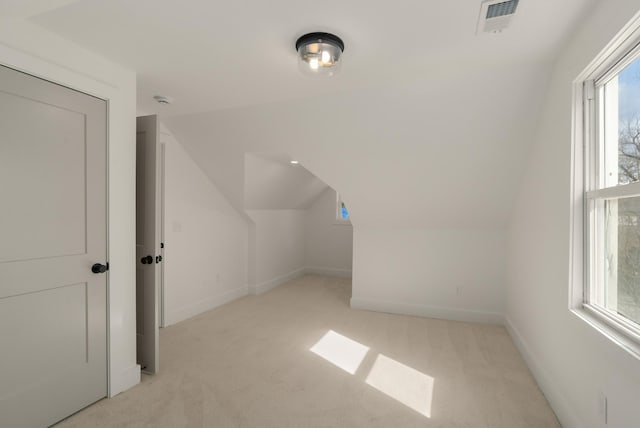 additional living space with lofted ceiling, light colored carpet, visible vents, and baseboards