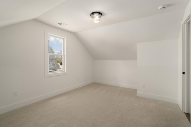 additional living space featuring light colored carpet, lofted ceiling, baseboards, and visible vents