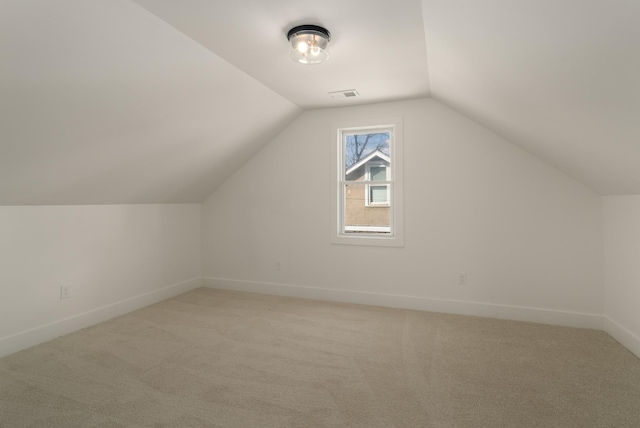 additional living space featuring visible vents, baseboards, light colored carpet, and vaulted ceiling