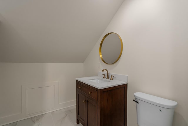 half bath with lofted ceiling, toilet, marble finish floor, and vanity
