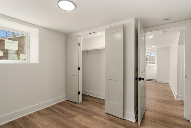 unfurnished bedroom featuring wood finished floors, baseboards, and a closet