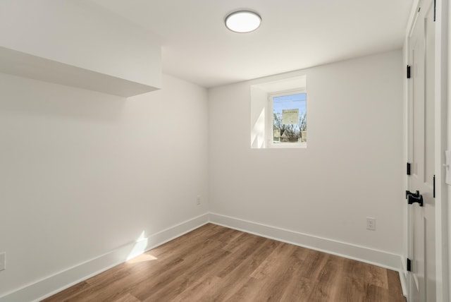 spare room with baseboards and light wood-style floors
