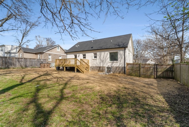 rear view of house featuring a deck, a lawn, a fenced backyard, and a gate