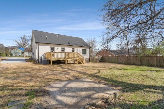 rear view of house with a shingled roof, fence, a wooden deck, cooling unit, and a yard