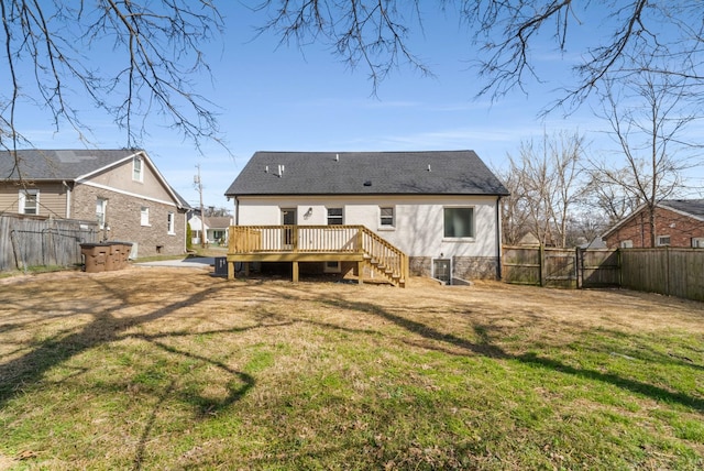 back of house with a yard, a wooden deck, a fenced backyard, and a gate