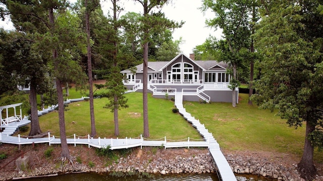 view of front of house featuring stairs, a front lawn, a chimney, and a water view