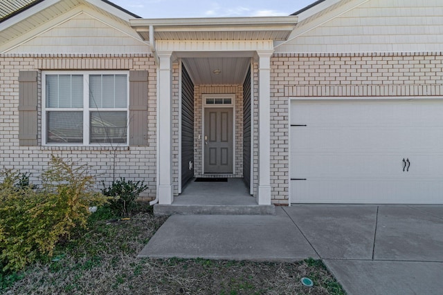 property entrance with an attached garage, brick siding, and driveway