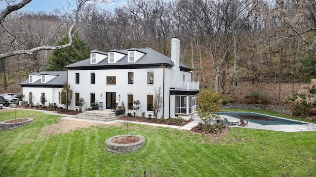 view of front of home featuring an outdoor fire pit, a balcony, and a front lawn