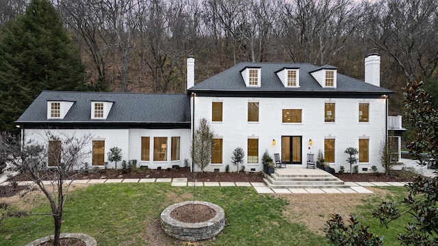 rear view of house with a yard, brick siding, and a chimney