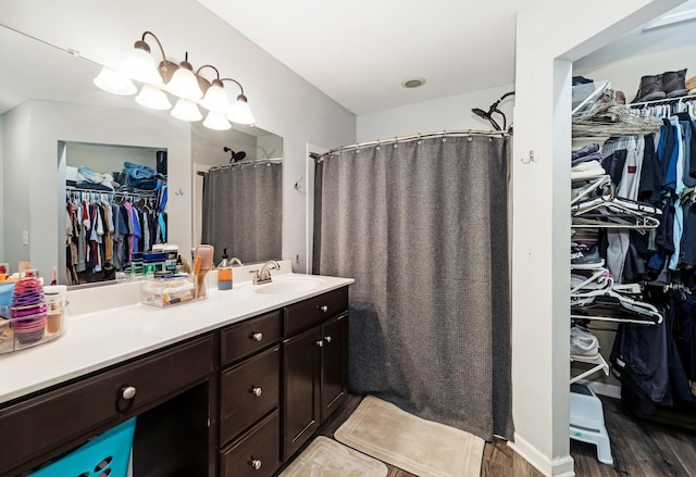 bathroom with a spacious closet, vanity, a shower with curtain, and wood finished floors