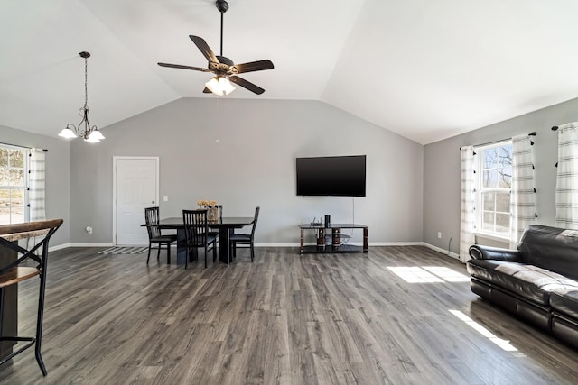 living room with ceiling fan with notable chandelier, baseboards, lofted ceiling, and wood finished floors