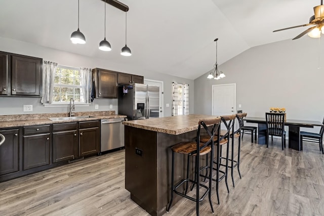 kitchen featuring light wood-style flooring, a sink, stainless steel appliances, a breakfast bar area, and dark brown cabinets