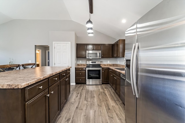 kitchen featuring a center island, stainless steel appliances, dark brown cabinetry, light wood finished floors, and vaulted ceiling