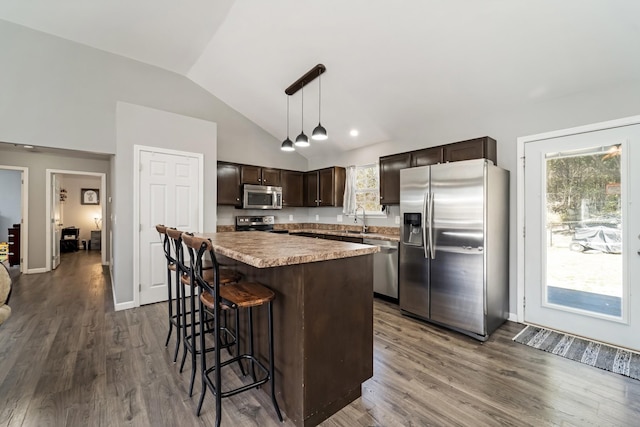 kitchen featuring a center island, dark brown cabinetry, lofted ceiling, appliances with stainless steel finishes, and dark wood-style floors