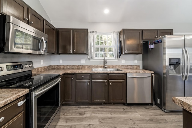 kitchen featuring dark brown cabinetry, light wood-type flooring, light countertops, stainless steel appliances, and a sink