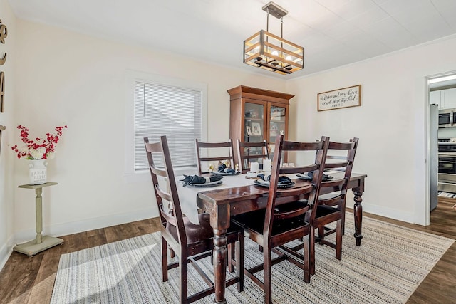 dining space featuring baseboards, a chandelier, and wood finished floors