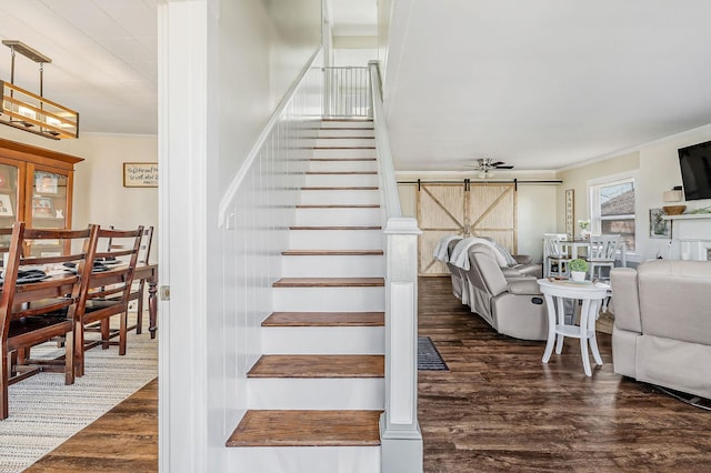 stairs featuring a barn door, ornamental molding, and wood finished floors