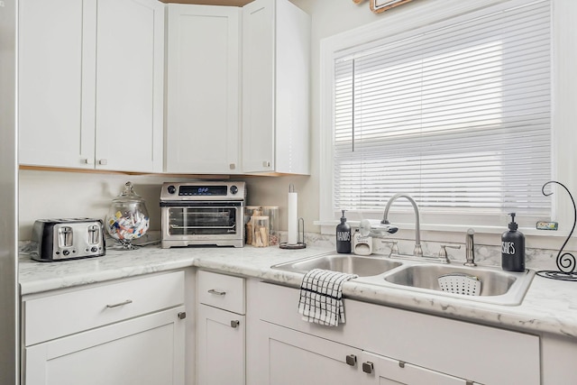 kitchen featuring a toaster, a sink, white cabinets, and a healthy amount of sunlight