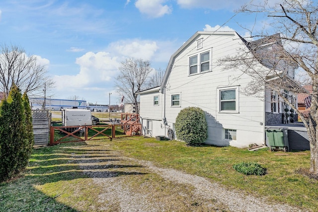 view of side of home featuring fence, a gambrel roof, driveway, a yard, and a gate