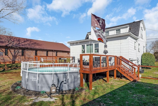 rear view of property featuring a gambrel roof, roof with shingles, a lawn, a wooden deck, and an outdoor pool